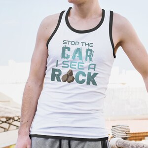 May include: White tank top with black trim and the text "Stop the Car I See a Rock" in blue and green with a graphic of three brown rocks.