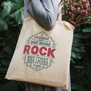 May include: A beige canvas tote bag with a vintage-style design featuring the text "I promise just one more rock but that one looks pretty good too".