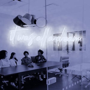 May include: Four people sit around a glass table in a modern office. A neon sign on the wall reads "it was all a dream".