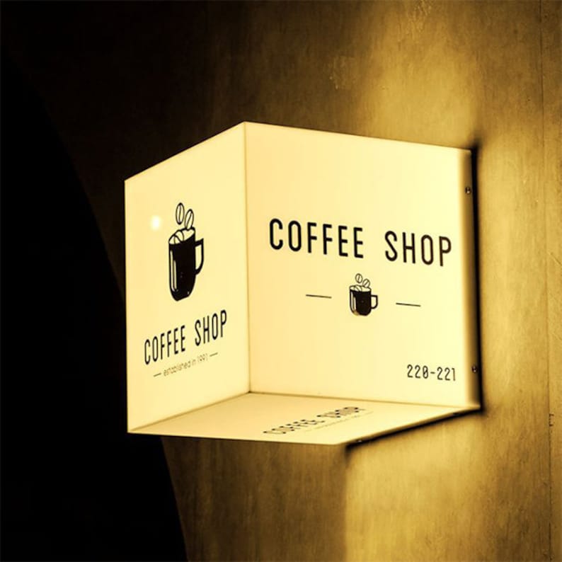 May include: A white illuminated sign with black text and a coffee cup logo. The sign reads "Coffee Shop" and has a phone number, "228-221".