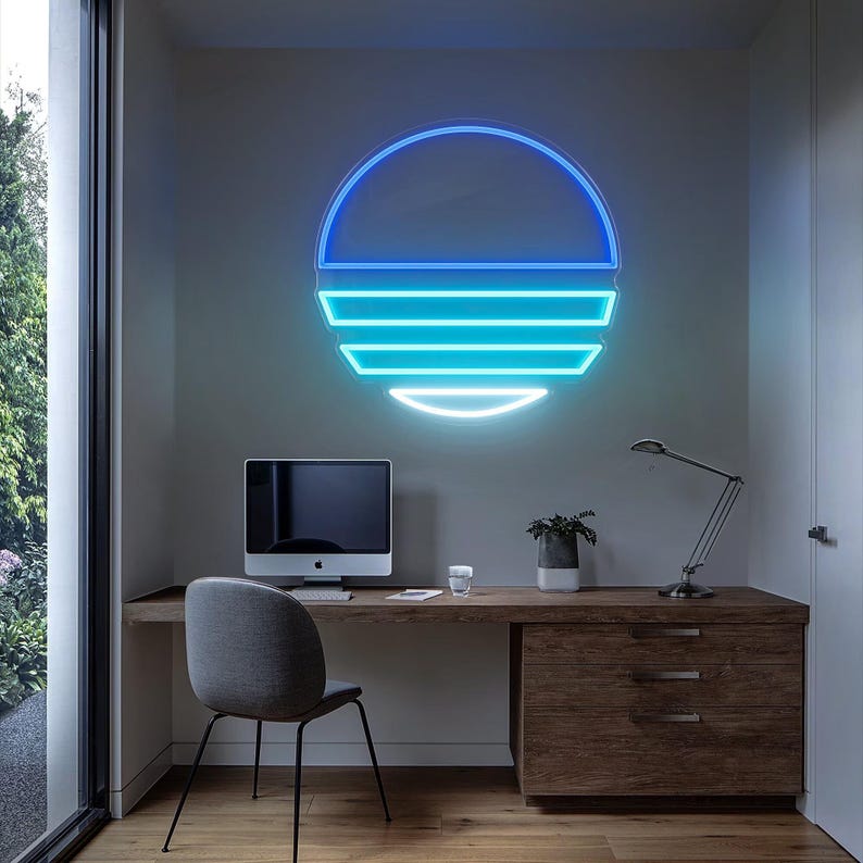May include: A blue and turquoise neon sign in the shape of a sun with horizontal lines. The sign is mounted on a white wall above a wooden desk with a computer, a lamp, and a plant.