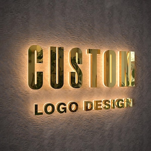 May include: Gold-colored, illuminated sign on a textured wall. The sign reads "CUSTOM" above "LOGO DESIGN" in a matching font. The letters have a reflective, metallic appearance, and the background is a neutral color.