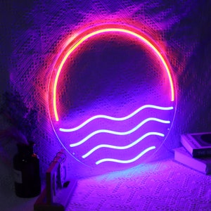 Puede incluir: Un letrero de ne&oacute;n con un c&iacute;rculo rosa y amarillo y olas azules. El letrero est&aacute; iluminado y brillando.