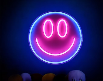 May include: A pink neon smiley face sign with a blue outline, hanging on a dark blue wall.