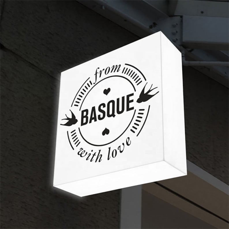 May include: White square sign with black text and graphics. The text reads "from with love" and "BASQUE" in a circle with two birds and hearts.