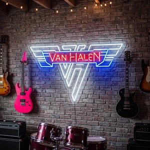 May include: A neon sign featuring the Van Halen logo in red and blue light, mounted on a brick wall. The sign displays the text Van Halen in red, surrounded by blue and white geometric wing shapes. The sign is centered above a drum kit.
