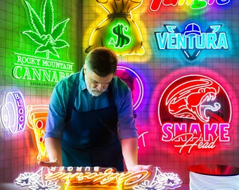May include: A man working with various neon signs, including a green cannabis leaf, a money bag with a dollar sign, and the words "Tangle" and "Ventura." The signs are in vibrant colors, and the man is wearing a blue shirt and apron.