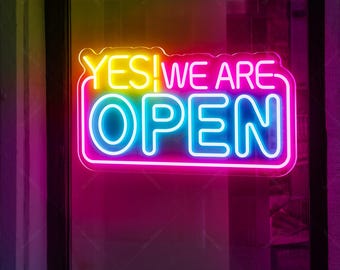 May include: A neon sign with the words "YES! WE ARE OPEN" in rainbow colors. The sign is lit up and glowing.