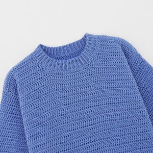 May include: A blue knitted sweater with a round neckline.
