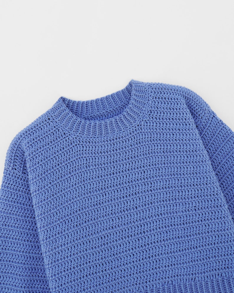 May include: A blue knitted sweater with a round neckline.