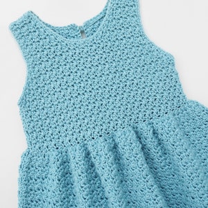 May include: A light blue crocheted sleeveless dress with a round neckline.