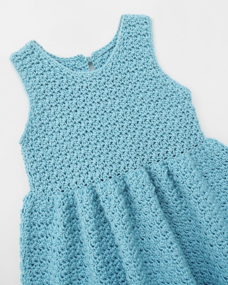 May include: A light blue crocheted sleeveless dress with a round neckline.