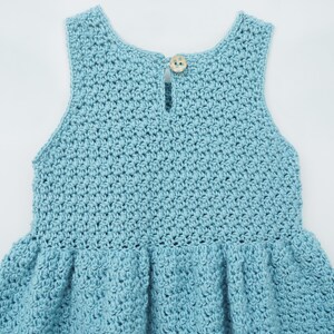 May include: A light blue crocheted dress with a button on the back.