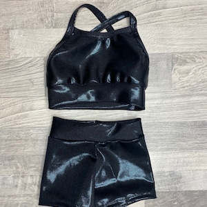 Peut inclure: Un haut de sport noir brillant avec un dos crois&eacute; et un short noir brillant assorti.