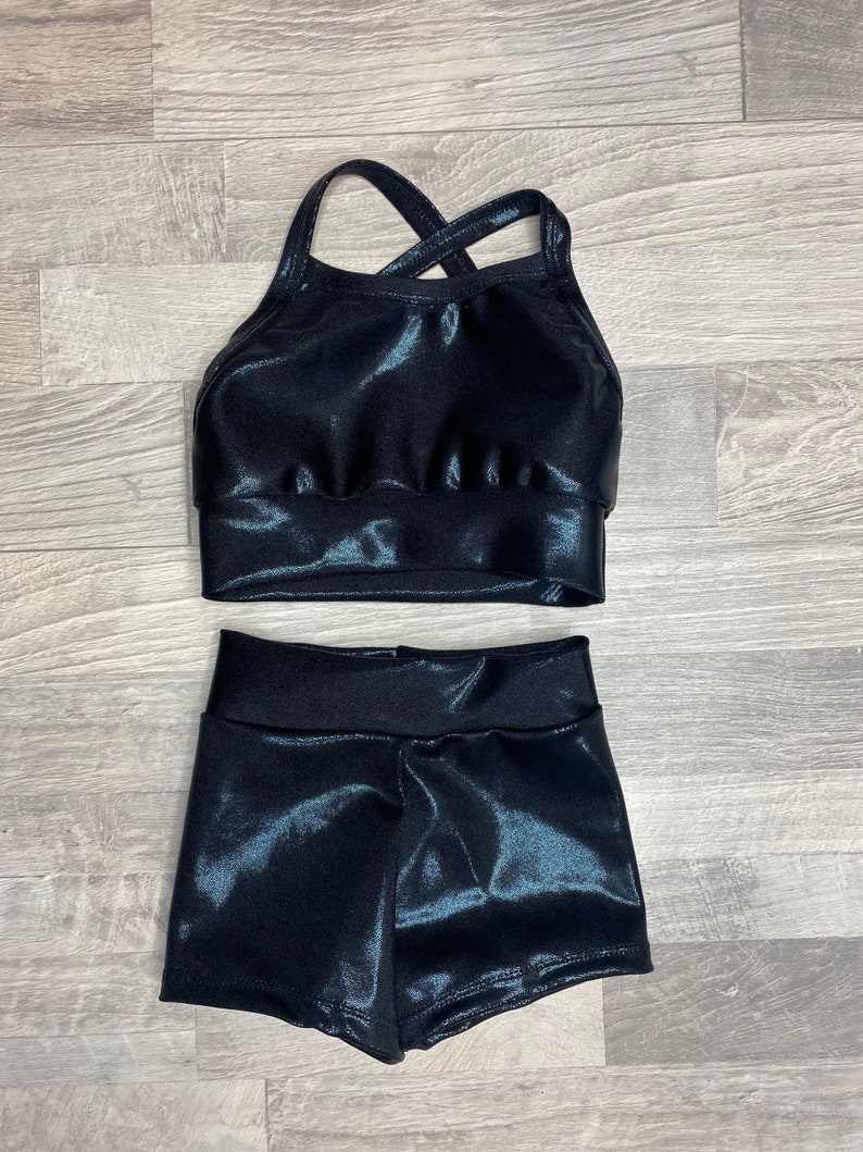 Peut inclure: Un haut de sport noir brillant avec un dos crois&eacute; et un short noir brillant assorti.