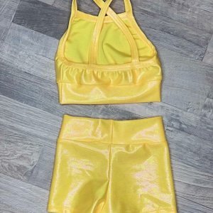 Peut inclure: Un justaucorps de danse jaune avec un dos crois&eacute; et un short assorti. Le tissu a une finition chatoyante.