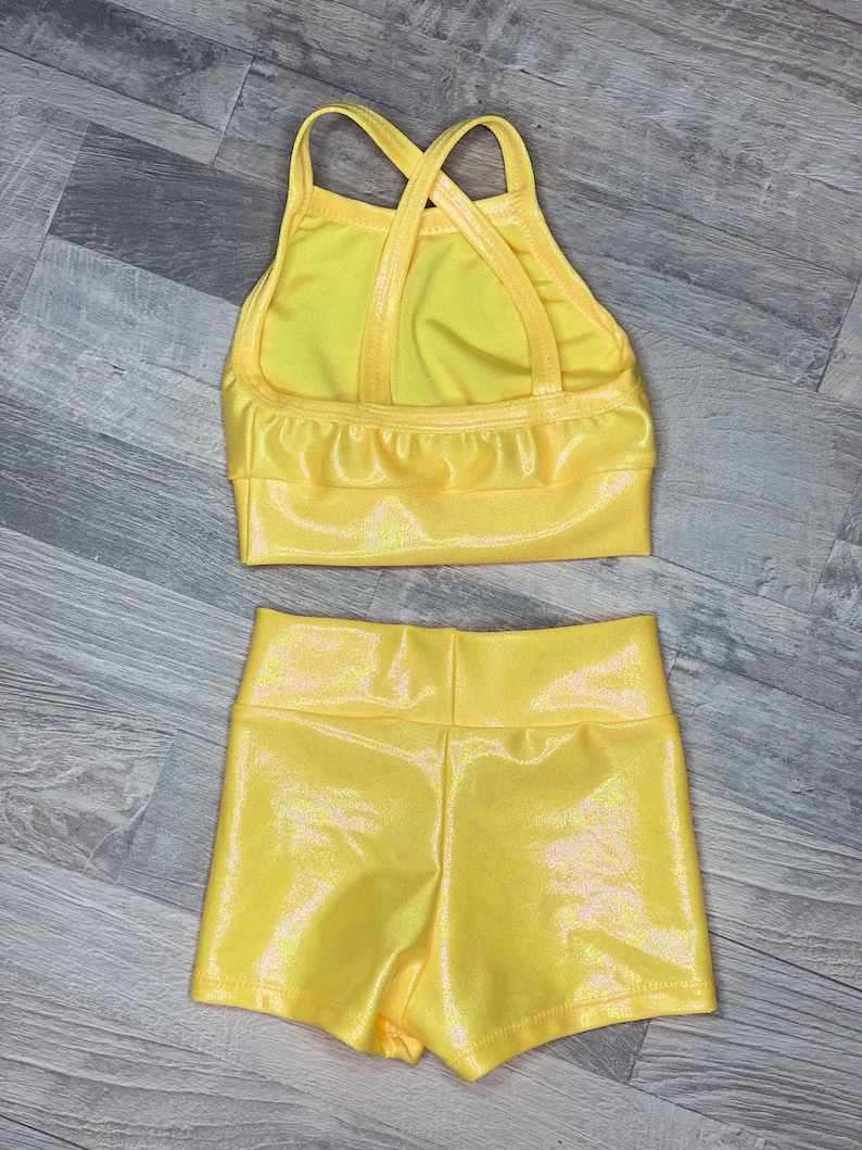 Peut inclure: Un justaucorps de danse jaune avec un dos crois&eacute; et un short assorti. Le tissu a une finition chatoyante.