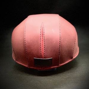 May include: A burgundy leather baseball cap with a black leather patch on the back.