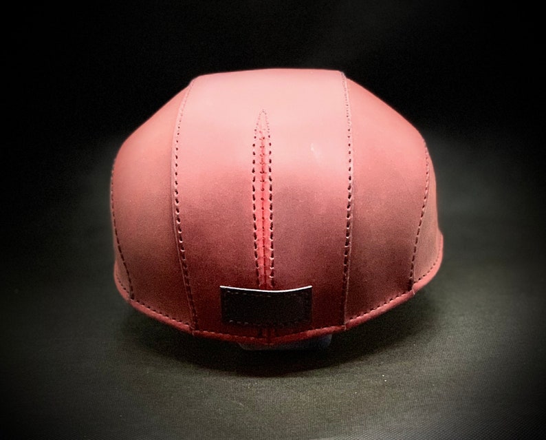 May include: A burgundy leather baseball cap with a black leather patch on the back.