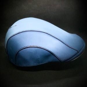 May include: A blue leather newsboy cap with a stitched seam detail.