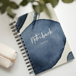 Könnte beinhalten: Ein blaues und weißes Notizbuch mit Spiralbindung, auf dem das Wort "Notizbuch" und der Name "Martin" stehen.