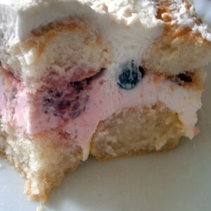 May include: A close-up of a slice of cake with whipped cream, blueberries, and a pink layer. The cake is on a white plate.