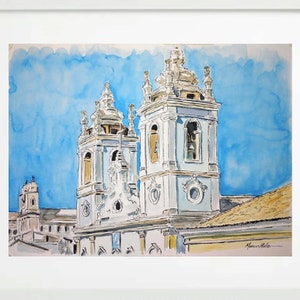 May include: Watercolor painting of two white church towers with blue accents against a bright blue sky. The towers have bell towers and ornate details. The painting is signed "Maria Leite" in the bottom right corner.