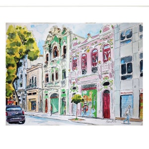 May include: Watercolor painting of a street scene with colorful buildings. The buildings have ornate details and are painted in shades of pink, green, and yellow. There is a tree on the left side of the painting and a car parked in the street.
