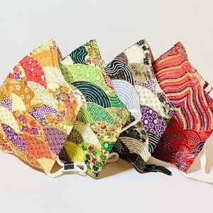 May include: Five fabric face masks with different patterns. The masks are made of a colorful patterned fabric with gold accents. The masks are all folded and stacked on top of each other.