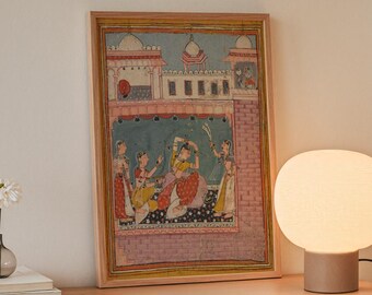 May include: A modern interior scene featuring a framed artwork depicting figures in traditional attire. A spherical, cream-colored lamp sits on a wooden shelf, next to the artwork. A small vase with a white flower and books are also on the shelf.
