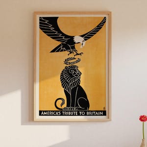 May include: Framed art print featuring a black eagle above a black lion, with a laurel wreath between them, set against a yellow background. The text "AMERICA'S TRIBUTE TO BRITAIN" is at the bottom. The print is in a wooden frame.