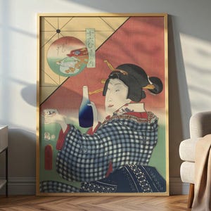 May include: Framed artwork featuring a Japanese geisha holding a bottle and cup. The geisha wears a checkered kimono and has her hair styled with decorative pins. The background includes a red and green design with Japanese text. The artwork is displayed in a room with a lamp and chair.