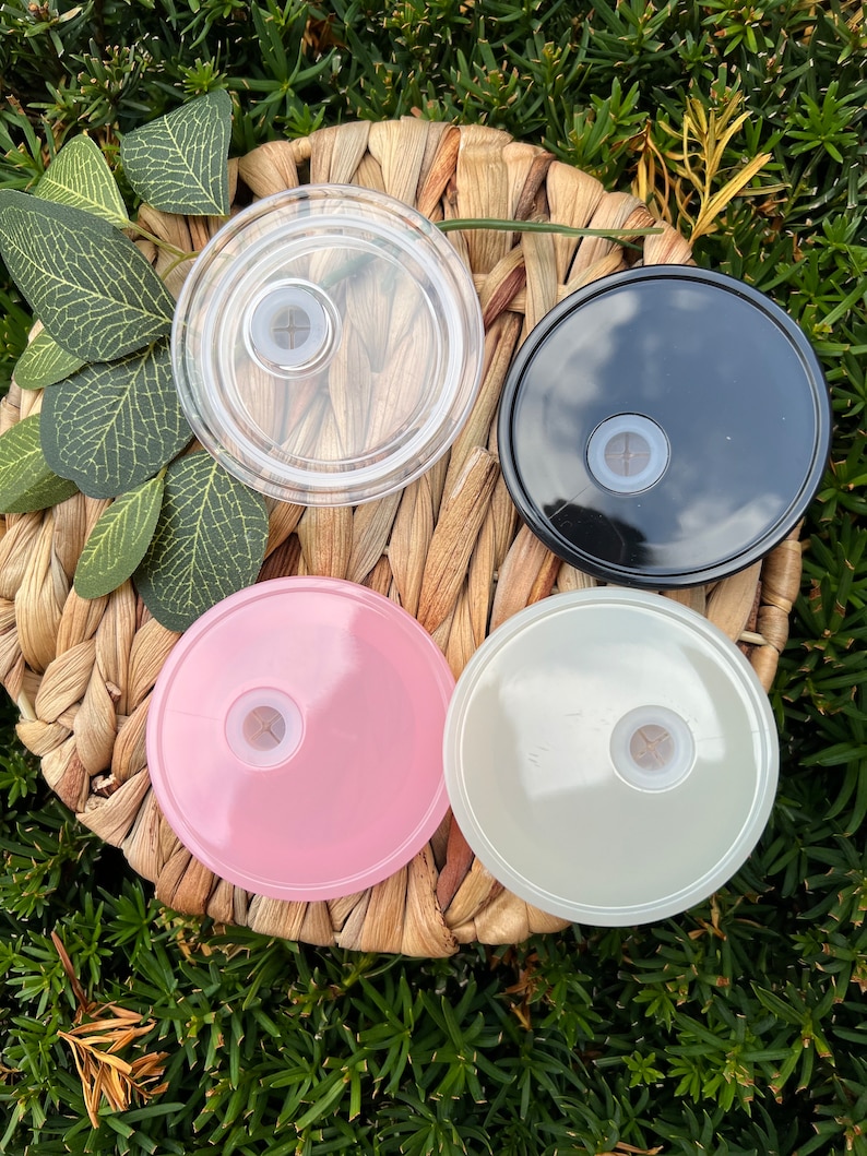 May include: Four round lids for a tumbler or cup. The lids are in four colors: clear, black, pink, and white. Each lid has a small hole in the center.