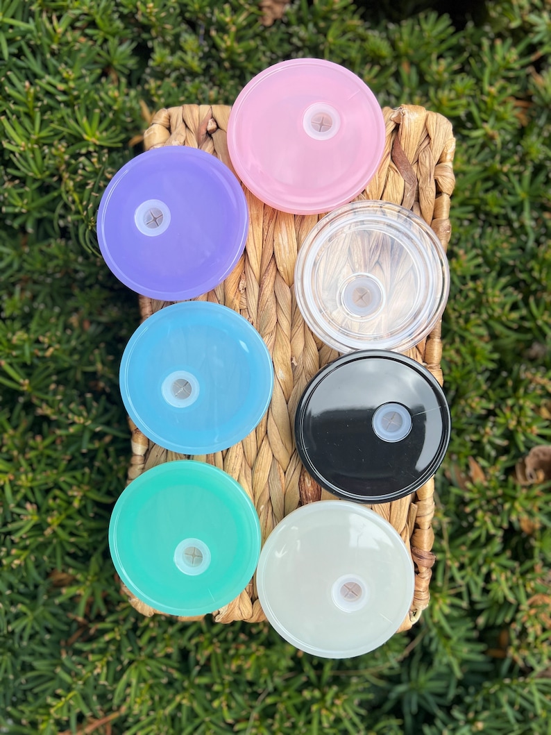 May include: Seven different colored plastic lids for a tumbler or cup. The lids are in a variety of colors, including pink, purple, blue, green, white, black, and clear.
