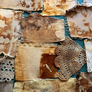 May include: A collection of assorted fabric scraps featuring various shades of brown, tan, and cream. The pieces include plain woven textiles with frayed edges, a piece with white eyelet lace trim, and a circular crocheted doily, all stained.