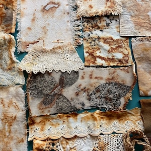 May include: A collection of assorted fabric scraps featuring botanical eco-prints in shades of brown, rust, and cream. The pieces include textured linen, frayed edges, and delicate white lace trim with intricate floral patterns and leaf imprints.