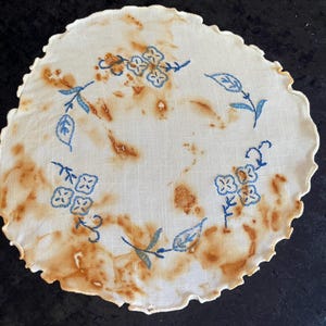 May include: A handmade wooden sign with the text "Welcome" in a playful font. The sign is painted white with a distressed finish, and features a decorative floral design in shades of pink and green. It measures approximately 12 inches wide.