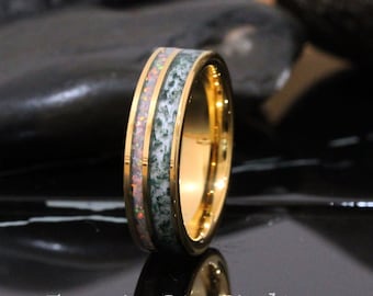 May include: A gold tungsten carbide ring with a green and white inlay. The ring has a polished finish and a bevelled edge.