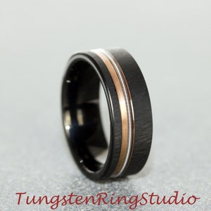 May include: A black tungsten ring with a brushed finish and two thin rose gold bands.