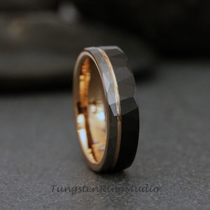Puede incluir: Un anillo de carburo de tungsteno negro con una incrustación de oro rosa. El anillo tiene un acabado martillado.