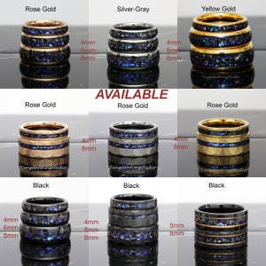 Op de afbeelding: Een set van drie ringen van wolfraamcarbide in verschillende kleuren, waaronder ros&eacute;goud, zilvergrijs, geelgoud en zwart. Elke ring heeft een blauwe en zwarte inlay en is verkrijgbaar in 4 mm, 6 mm en 8 mm breedte. De ringen worden getoond op een witte achtergrond.