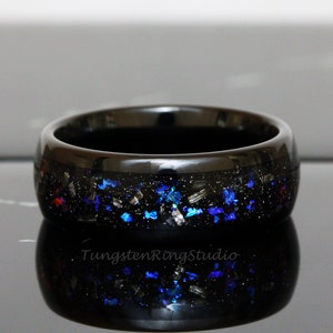 May include: Black tungsten ring with blue and silver glitter embedded in the band. The ring is polished and has a high shine.