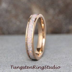 Könnte beinhalten: Ein roségoldener Wolframcarbid-Ring mit einem weißen Opal-Inlay. Der Ring ist ein schlichtes Band mit einer dünnen Opal-Linie, die um die Mitte verläuft.