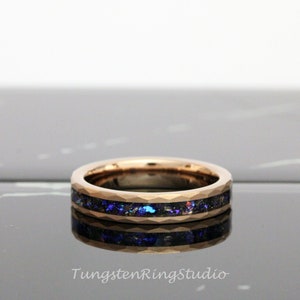 Op de afbeelding: Een ros&eacute;gouden ring van wolframcarbide met een zwarte en blauwe inlay. De ring heeft een afgeschuinde rand en een gepolijste afwerking.