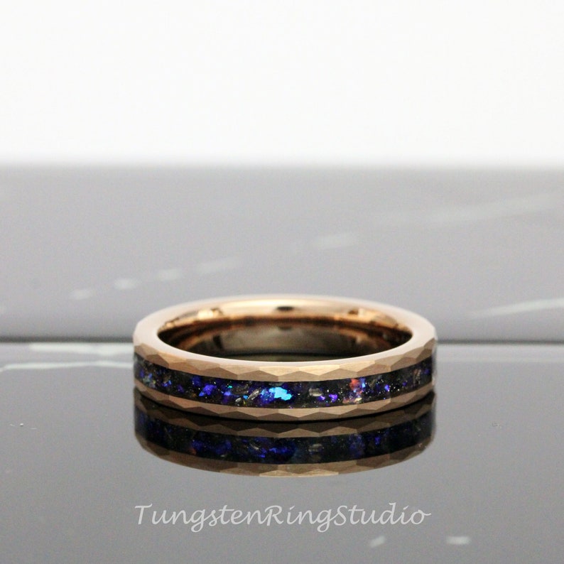 Op de afbeelding: Een ros&eacute;gouden ring van wolframcarbide met een zwarte en blauwe inlay. De ring heeft een afgeschuinde rand en een gepolijste afwerking.