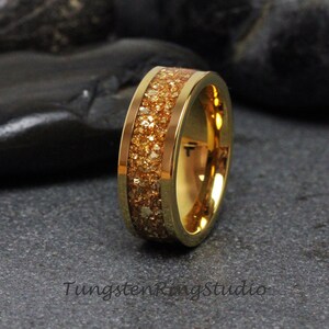May include: A gold tungsten carbide ring with a band of sparkly gold glitter. The ring is a classic style and is perfect for a wedding band or an everyday ring.