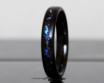 May include: A black tungsten carbide ring with a blue and silver glitter inlay. The ring is polished and has a smooth finish.