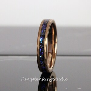Op de afbeelding: Een ros&eacute;gouden ring van wolframcarbide met een blauwe en zwarte inlay. De ring heeft een afgeschuinde rand en een gepolijste afwerking.