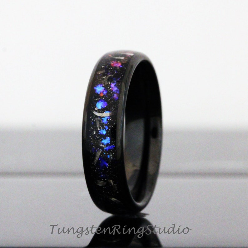 May include: Black tungsten carbide ring with a blue, pink and silver glitter inlay.