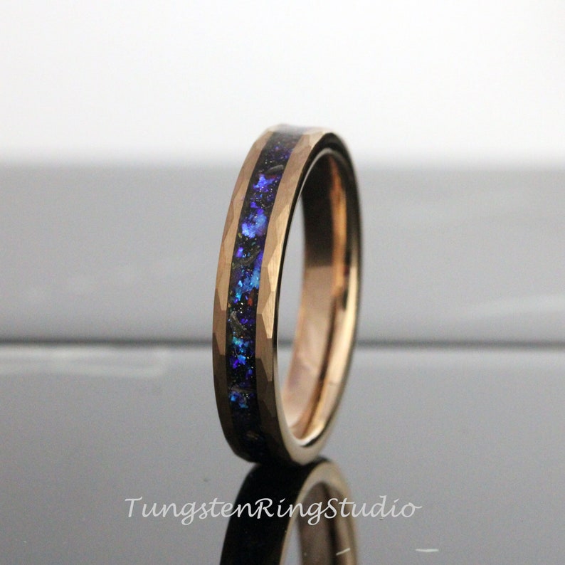Op de afbeelding: Een ros&eacute;gouden ring van wolframcarbide met een blauwe en zwarte inlay. De ring heeft een gehammerde afwerking.